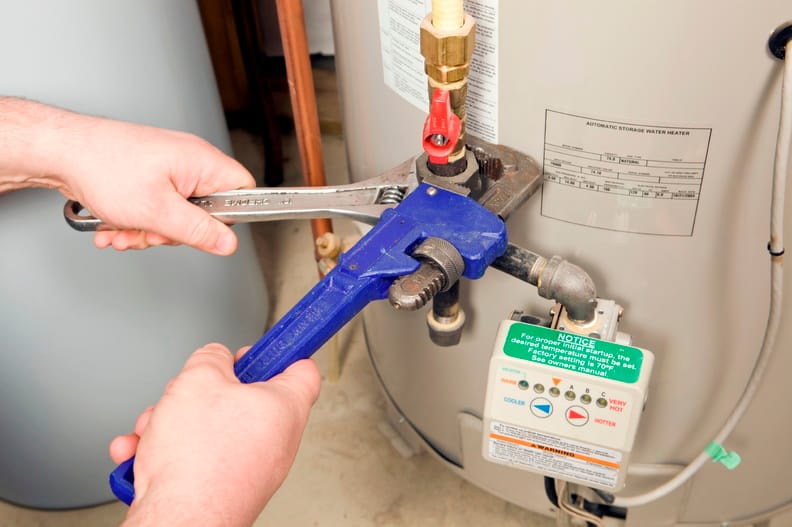 Plumber repairing water heater pipe connection in Melbourne, Florida home