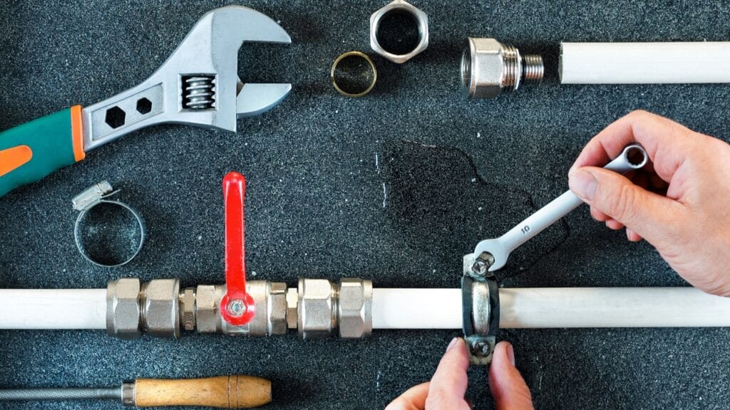 Plumber repairing a pipe valve with an adjustable wrench in Melbourne