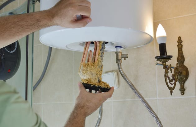 Technician removing mineral buildup from a water heater in Melbourne