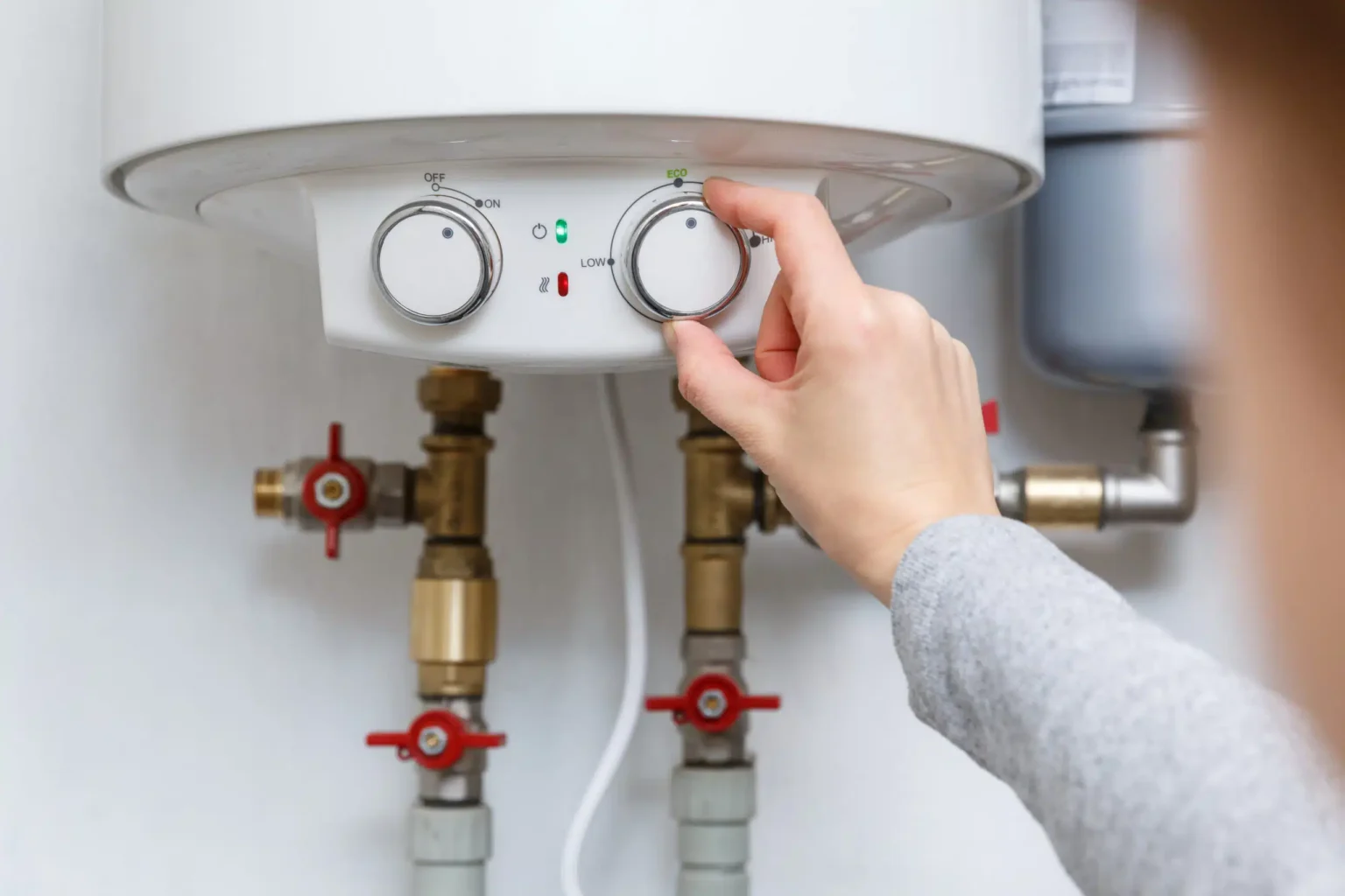 Homeowner adjusting the temperature controls on a water heater in Melbourne